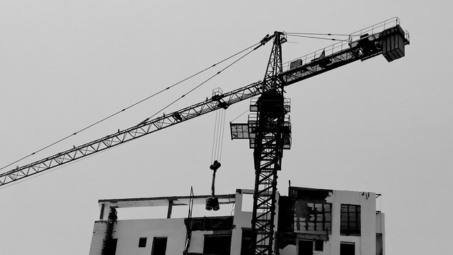 Black and white photo. Crane and building.